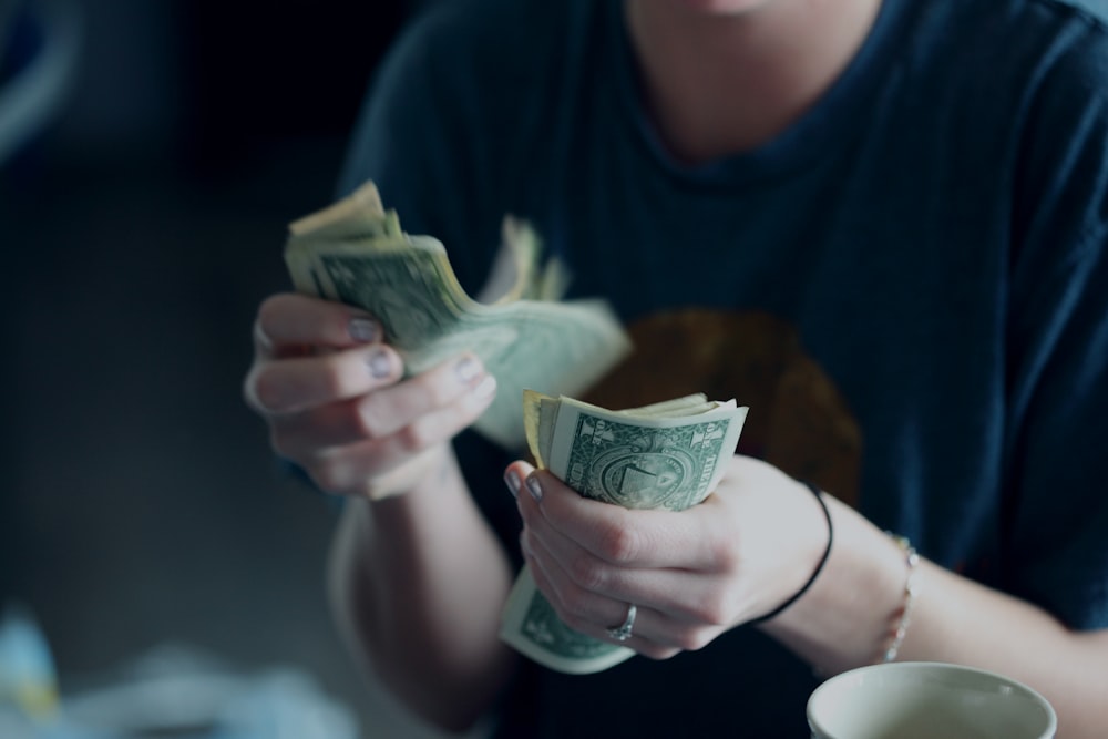 Fotografia di messa a fuoco della persona che conta le banconote da un dollaro