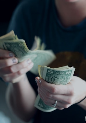 focus photography of person counting dollar banknotes