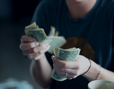 focus photography of person counting dollar banknotes