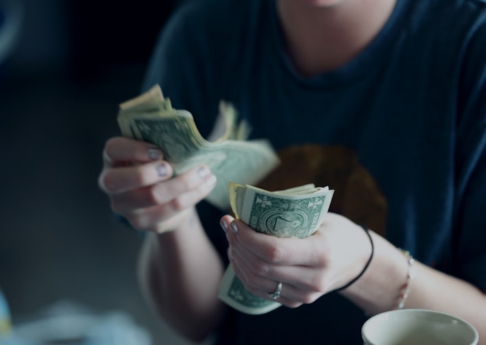 focus photography of person counting dollar banknotes