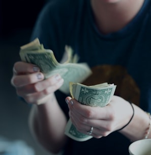focus photography of person counting dollar banknotes