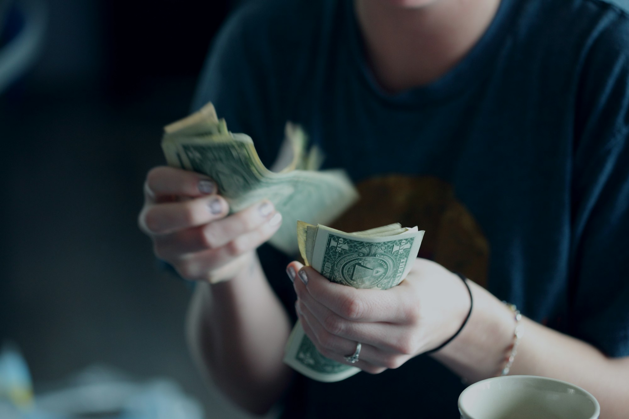 امرأة تبلغ من العمر أربعة وعشرين عامًا تحسب الأوراق النقدية بالدولار.