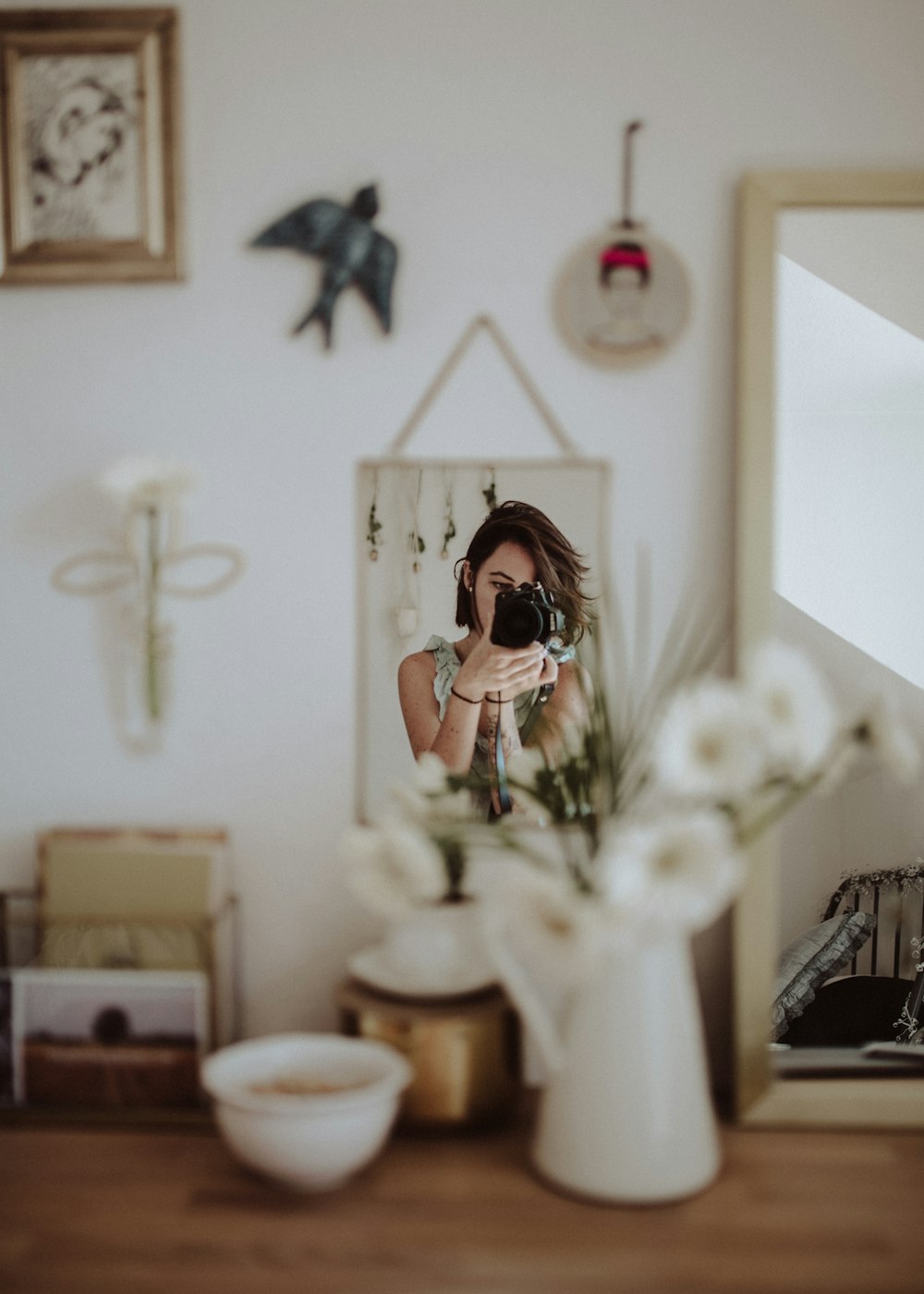 部屋の中のフロントミラーで写真を撮るデジタル一眼レフカメラを持っている女性