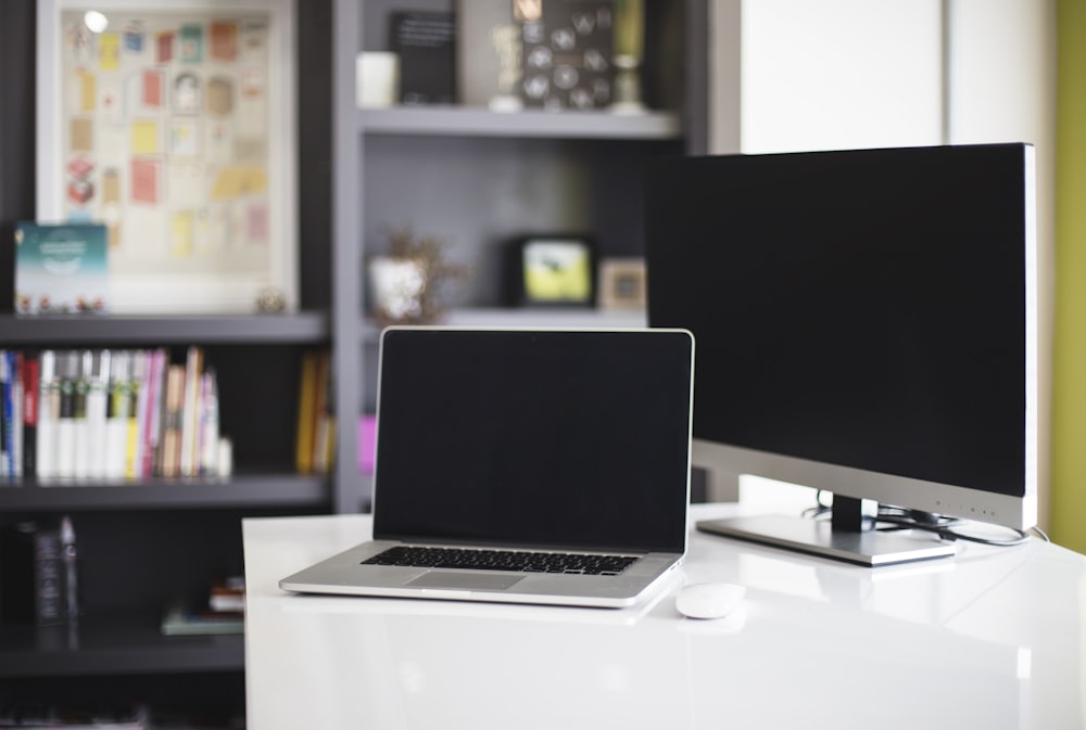 MacBook Pro beside silver monitor on table