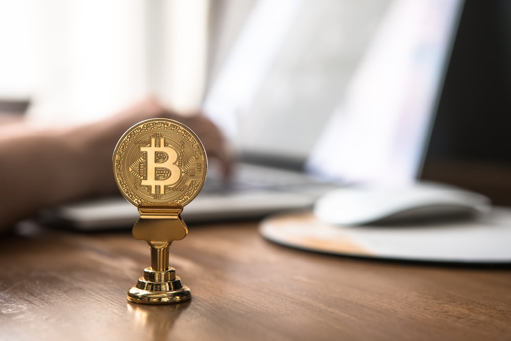 gold-colored bitcoin on brown table