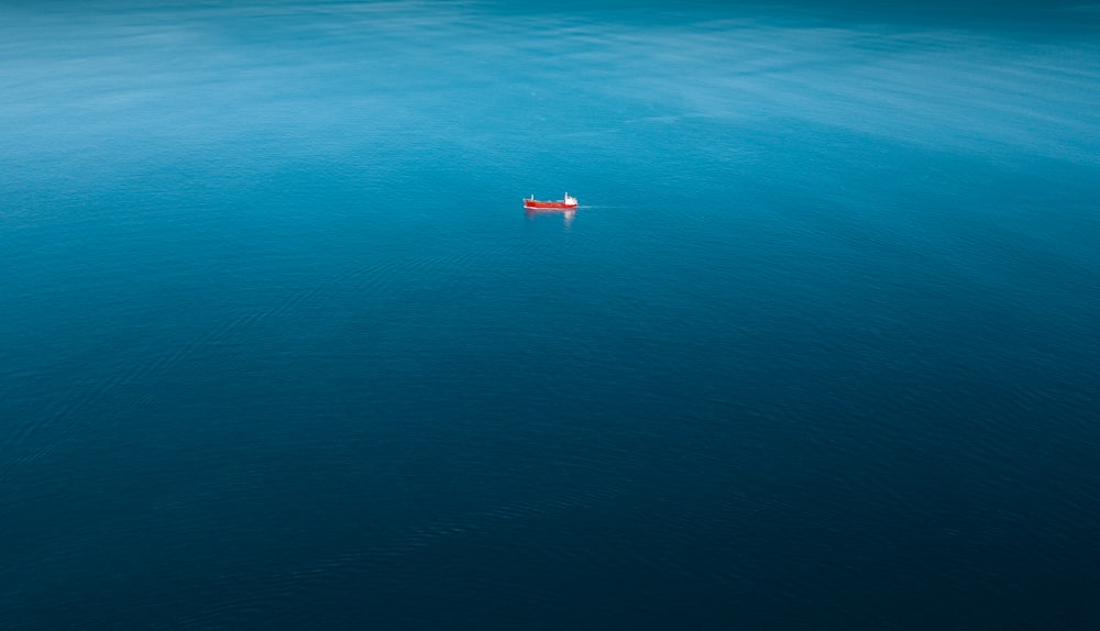 Barco rojo navegando solo en un cuerpo de agua