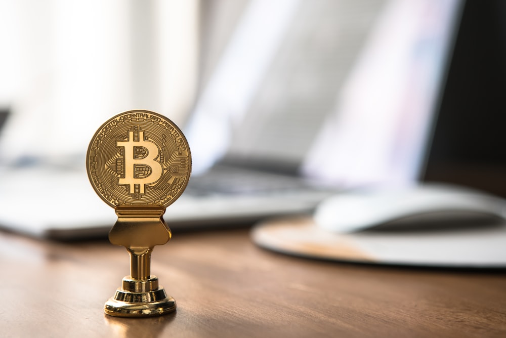round gold-colored bitcoin on table