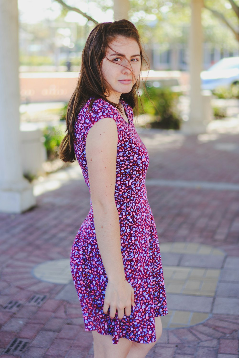 woman wearing purple and pink sleeveless dress standing beside concrete pillar