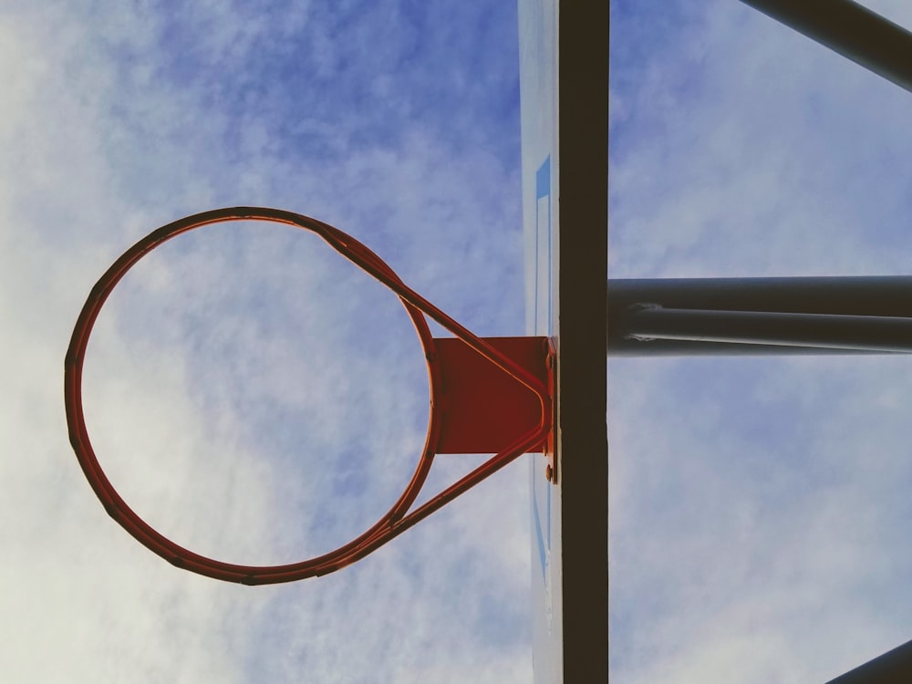 Aro de baloncesto naranja y negro bajo cielo blanco y azul