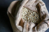 Stylish display of green unroasted coffee beans against a backdrop of warm, earthy textiles.