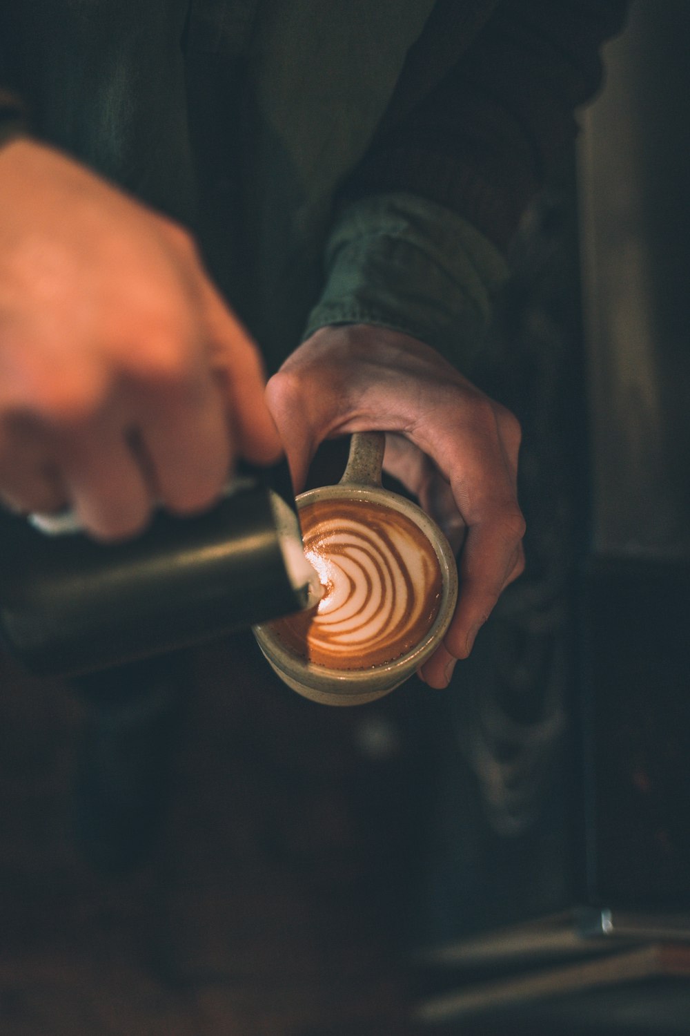 Mann gießt Latte Art in eine mit Kaffee gefüllte Tasse