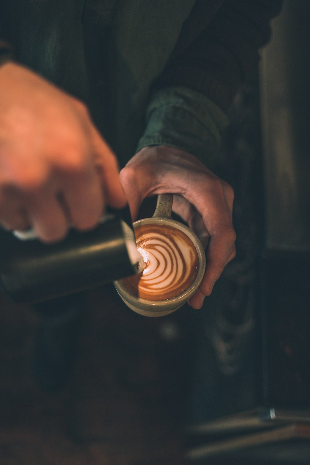 man pouring latte art to cup filled with coffee