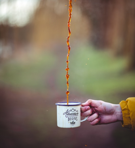 brown liquid poured on white enamel cup