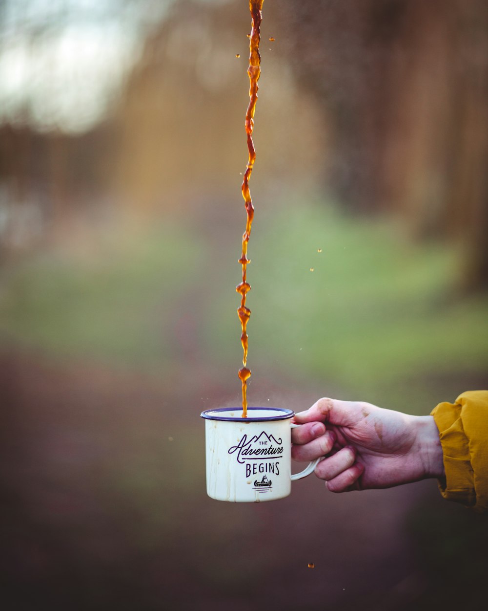 liquide brun versé sur une tasse en émail blanc