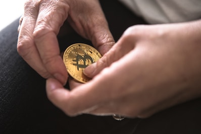 person holding round gold-colored Bitcoin