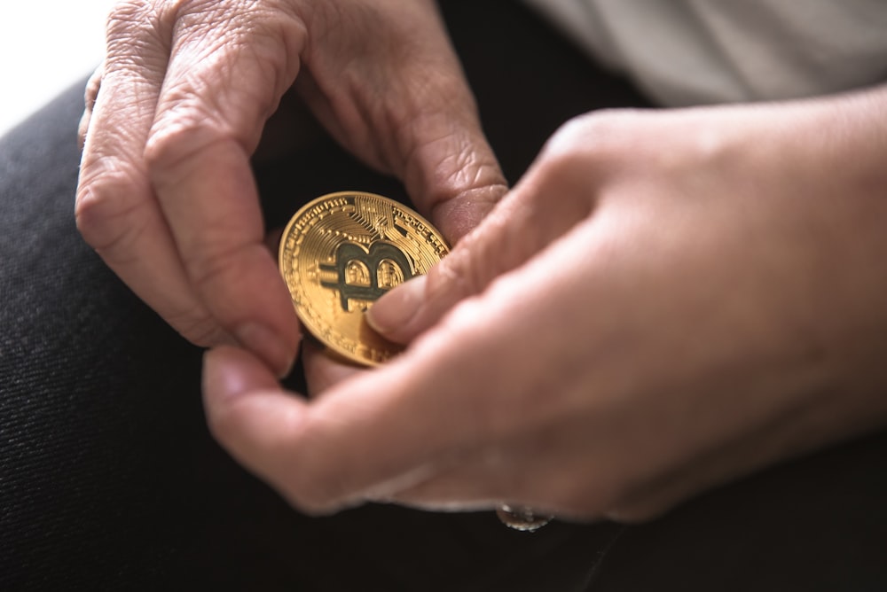 Person, die runde goldfarbene Bitcoin in der Hand hält