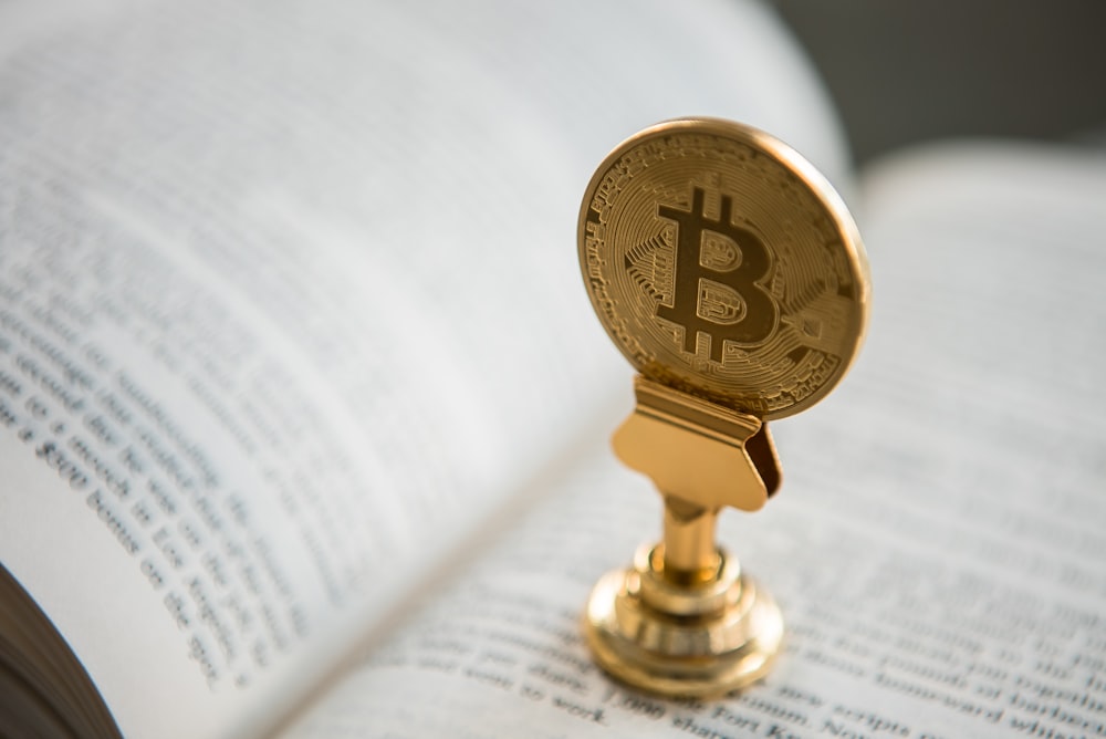 bitcoin on gold stand on top of book