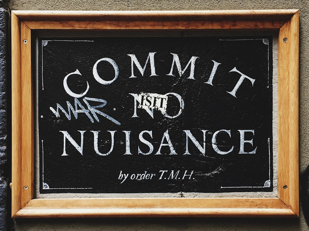 Commit No Nuisance signage with brown wooden frame