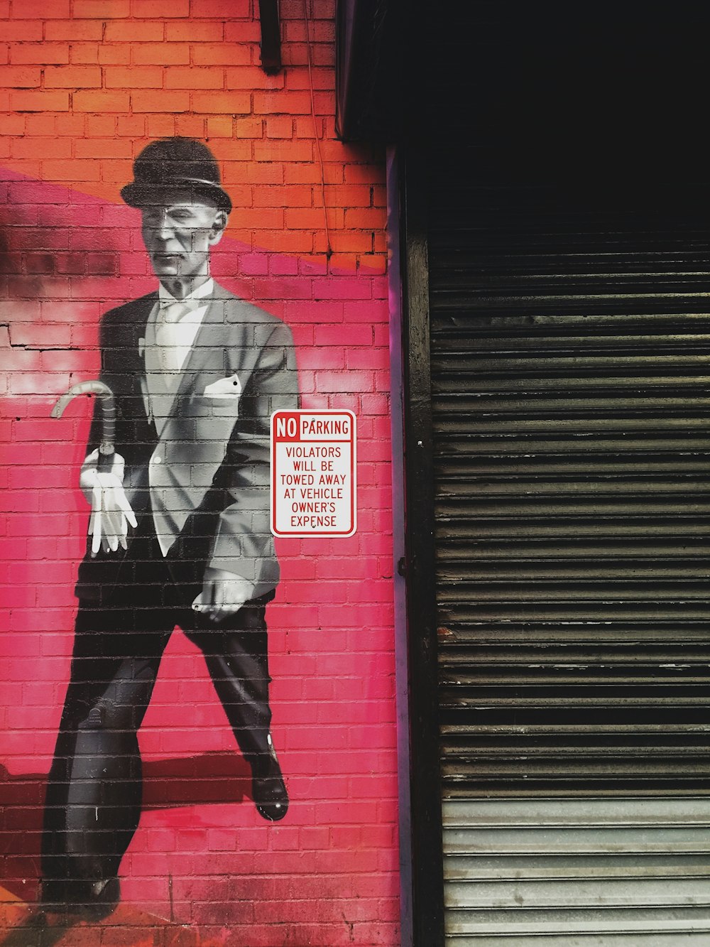 une peinture d’un homme en costume et chapeau sur un mur de briques