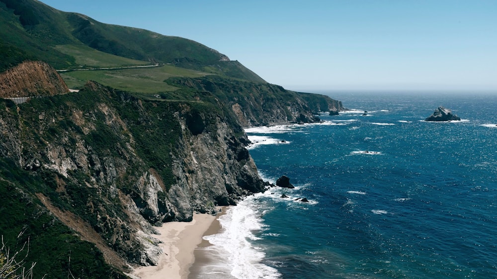 sea waves hitting seashore near rock mountain