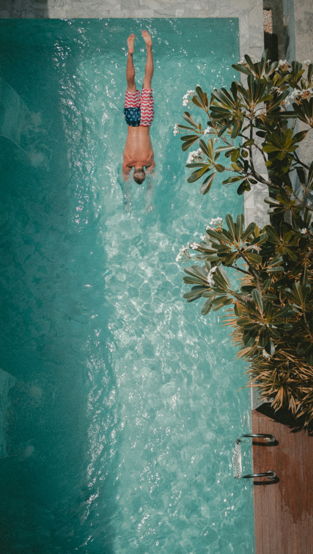 Photographie en plongée en plongée d’un homme vers la piscine