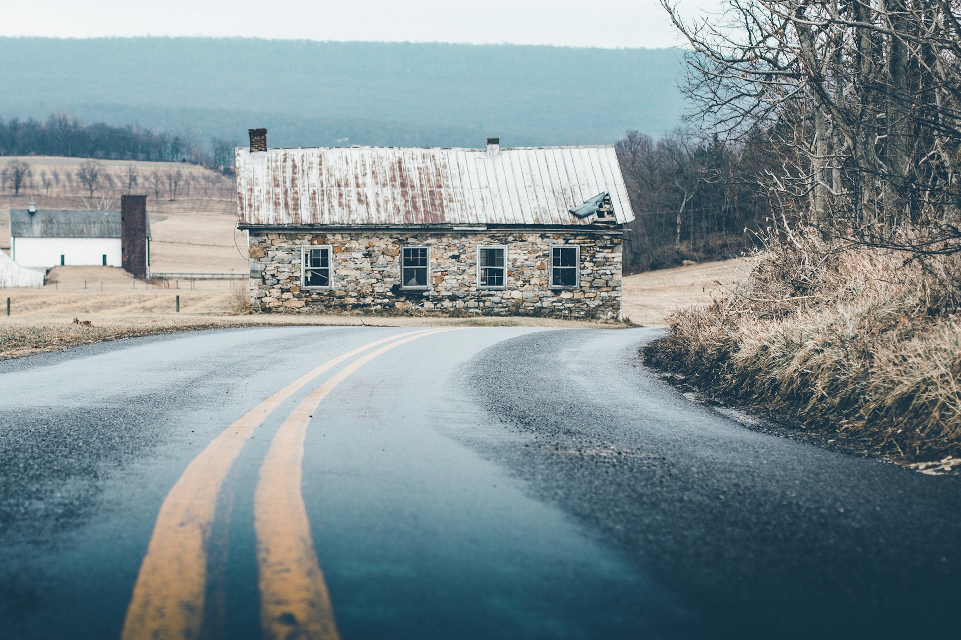 gray brick house beside road under cloudy sky