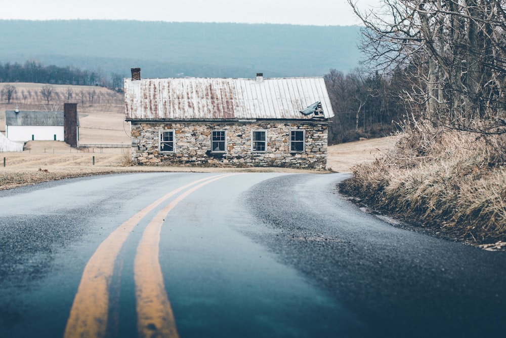 gray brick house beside road under cloudy sky