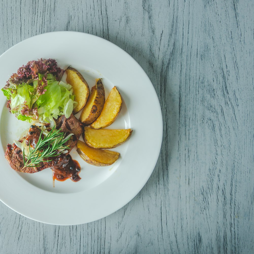 Kartoffelscheiben mit Fleisch und Salat auf dem Teller