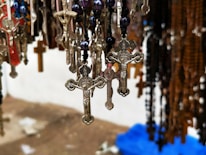 Close-up of delicate Catholic jewelry pieces with soft spring colors in the background.
