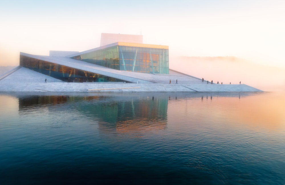 Bâtiment gris près d’un plan d’eau sous un ciel blanc