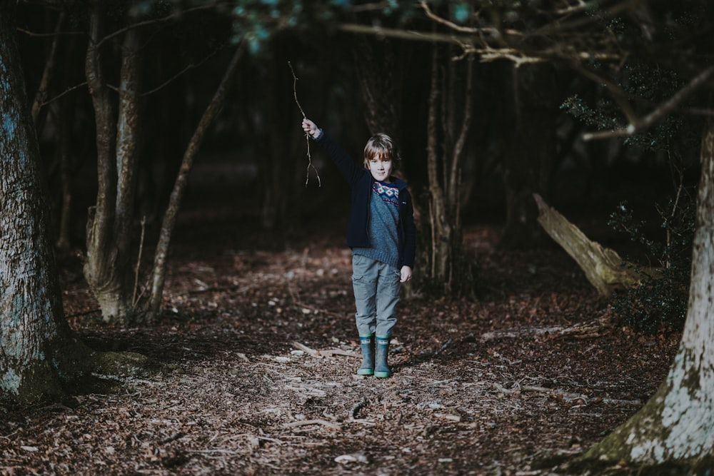 boy holding tree branch inside the forest