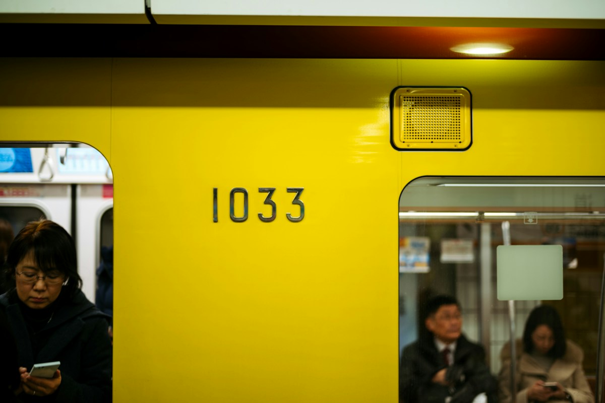 Interior of a yellow Tokyo subway train, empty seats along the wall