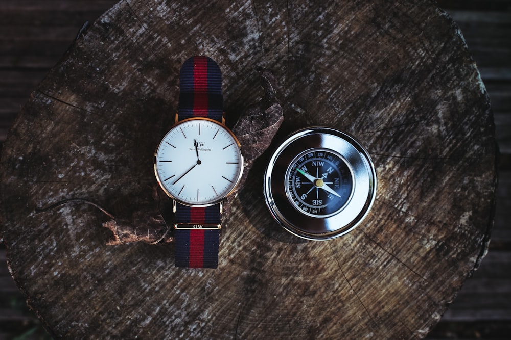 round brass-colored analog watch on top of brown surface