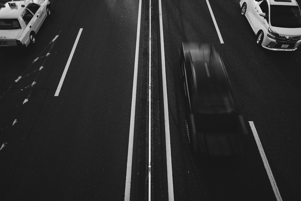 grayscale photo of running vehicles on road