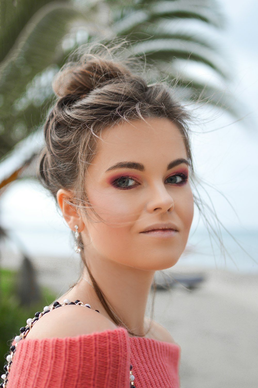 woman wearing red knit off-shoulder top looking sideways