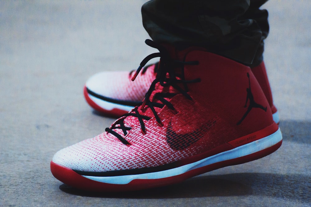 pessoa vestindo par de sapatos de basquete Air Jordan vermelho-e-branco