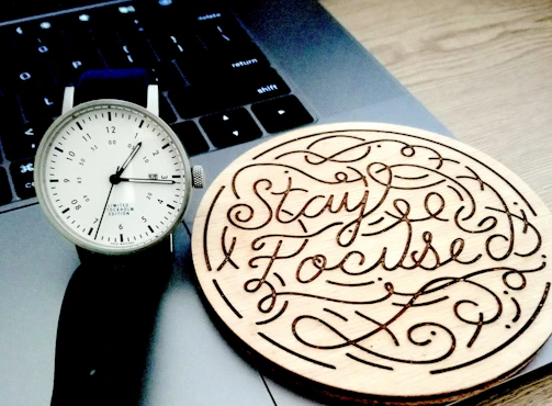A minimalist wristwatch worn by a person typing on a laptop in a cozy café.