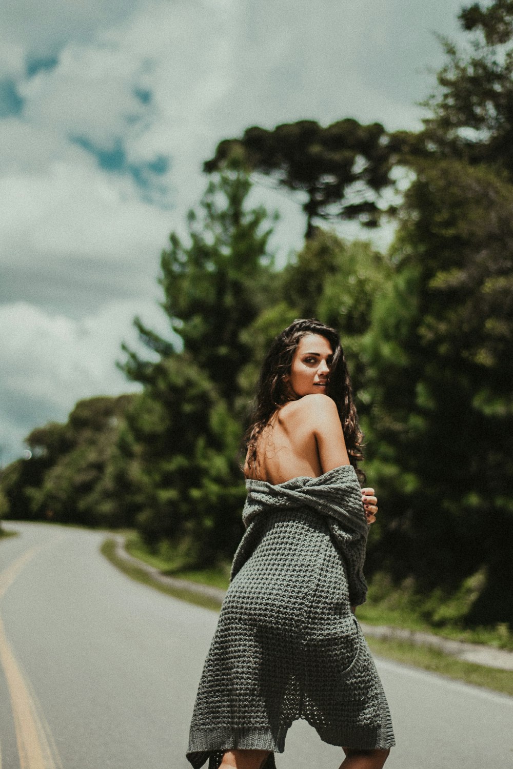 woman showing her shoulder while standing on the middle of the road