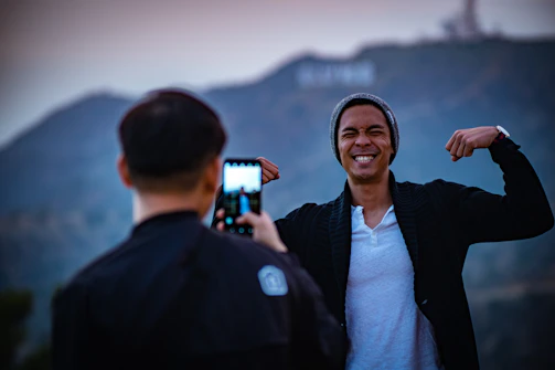A man smiling confidently as he compares his before and after fitness photos on a tablet.