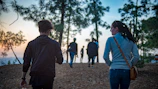 Sunset over a forest trail with hikers walking together
