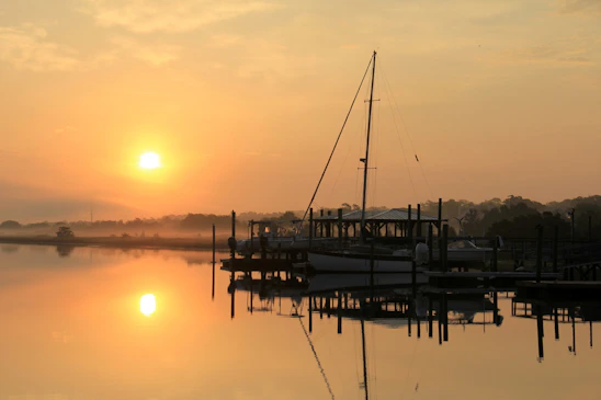 A serene harbor at sunrise with calm waters reflecting soft pastel skies, symbolizing peace and new beginnings.
