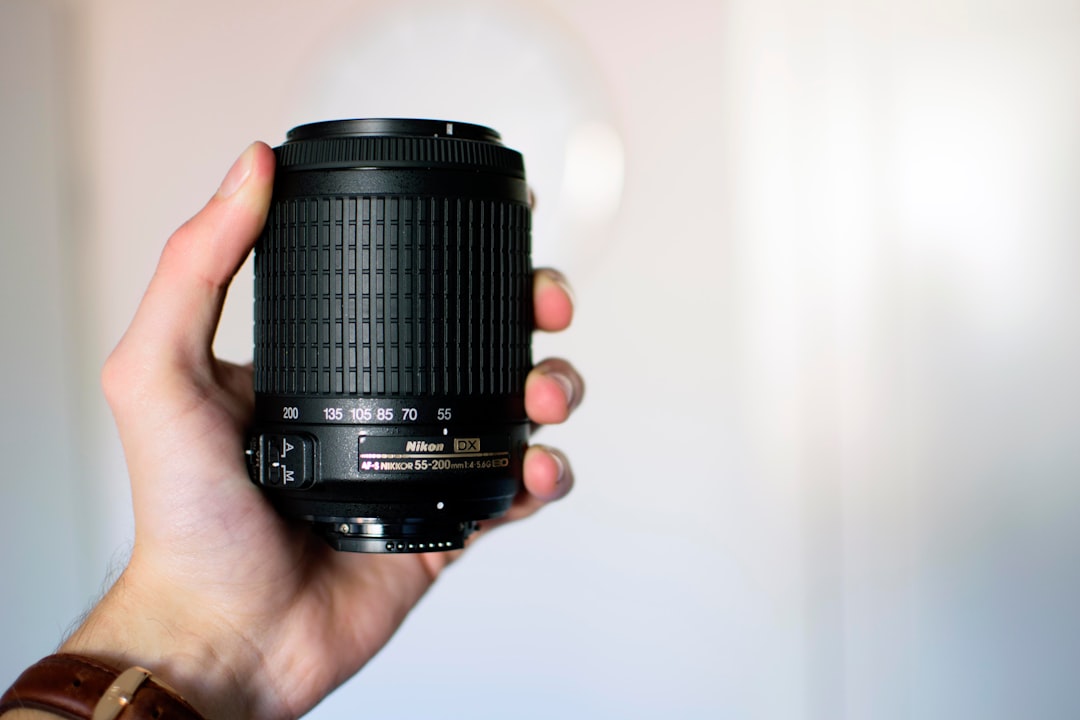 person holding black Nikon camera lens, Nikon Lens
