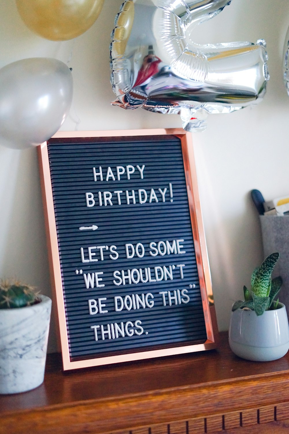 gray and black birthday quote-printed decor beside green snake plant