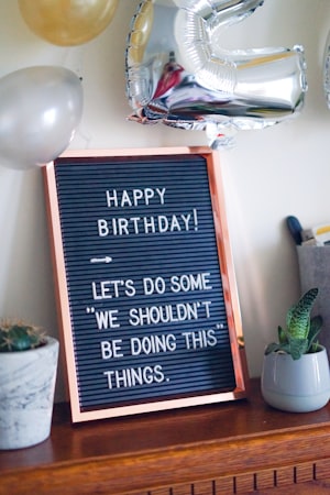 gray and black birthday quote-printed decor beside green snake plant