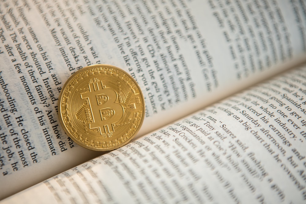 gold-colored Bitcoin on book
