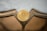 A golden Bitcoin token is placed against a reflective surface with geometric shapes and a lightly textured background.