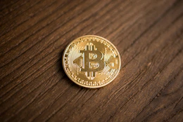 A close-up of a bitcoin coin on a wooden table.