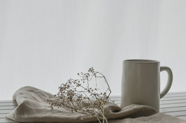 Un pot en grès gris, du lin et une branche séchée