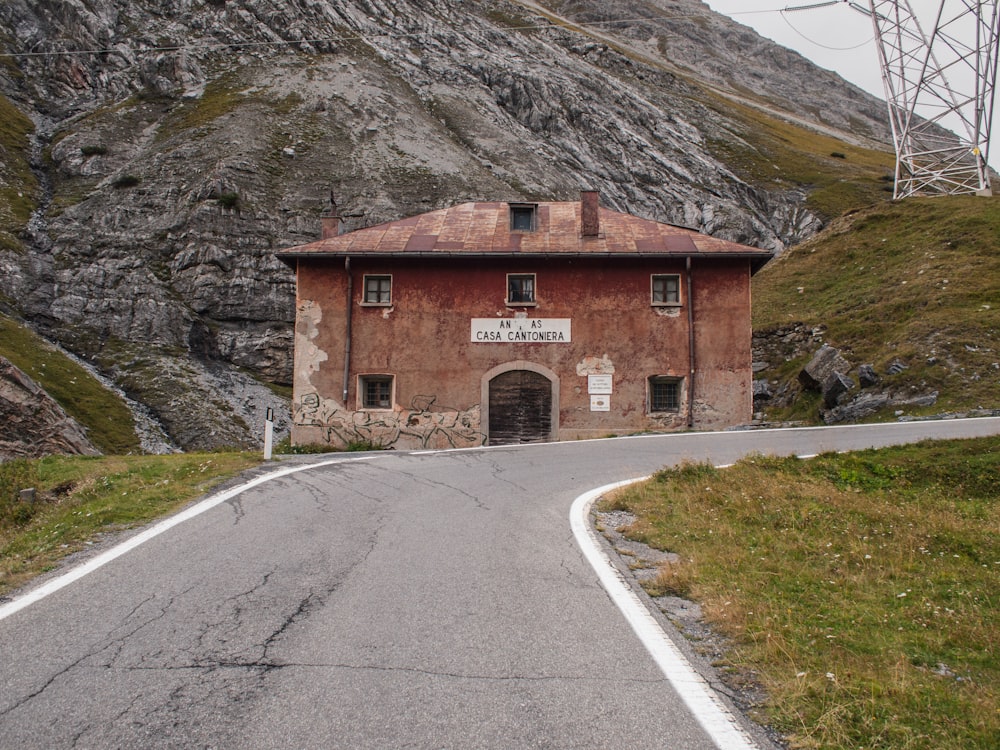 brown brick building beside curved blacktop road