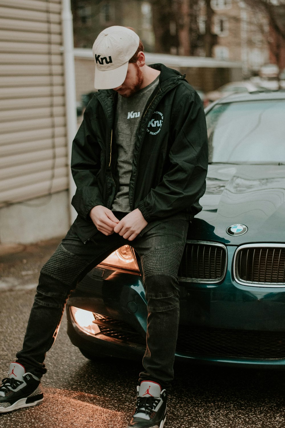 man in black jacket sitting on car